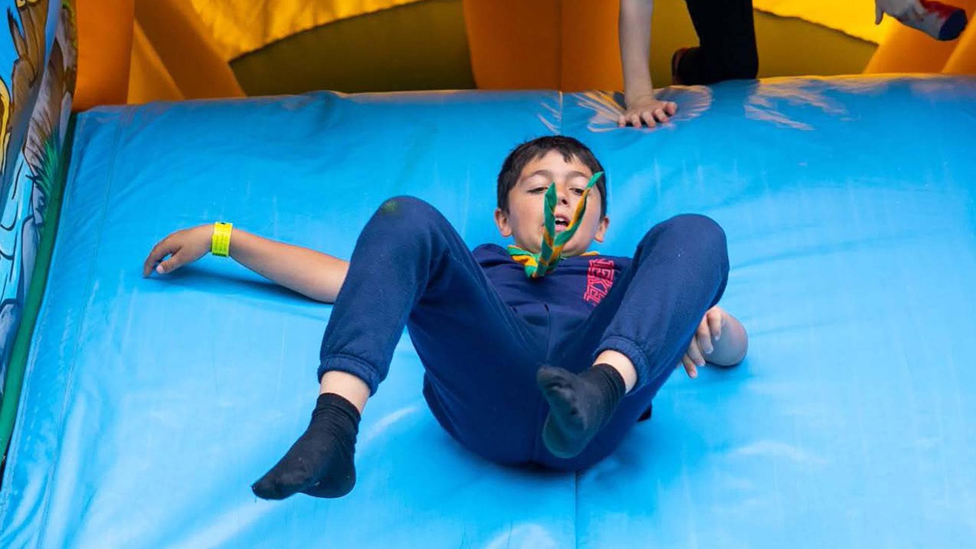 Image of a scout sliding down a bouncy castle slide.
