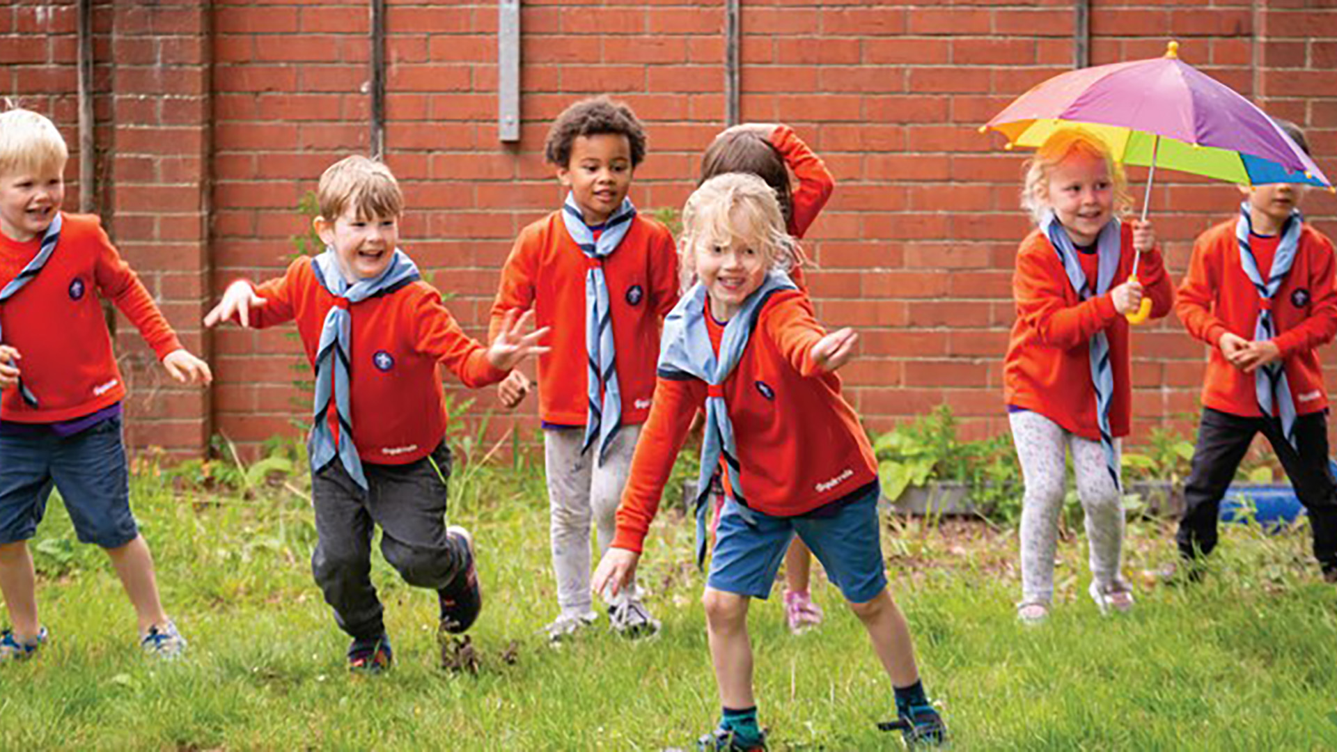 Young children in Squirrel uniforms playing a wide game with an umbrella